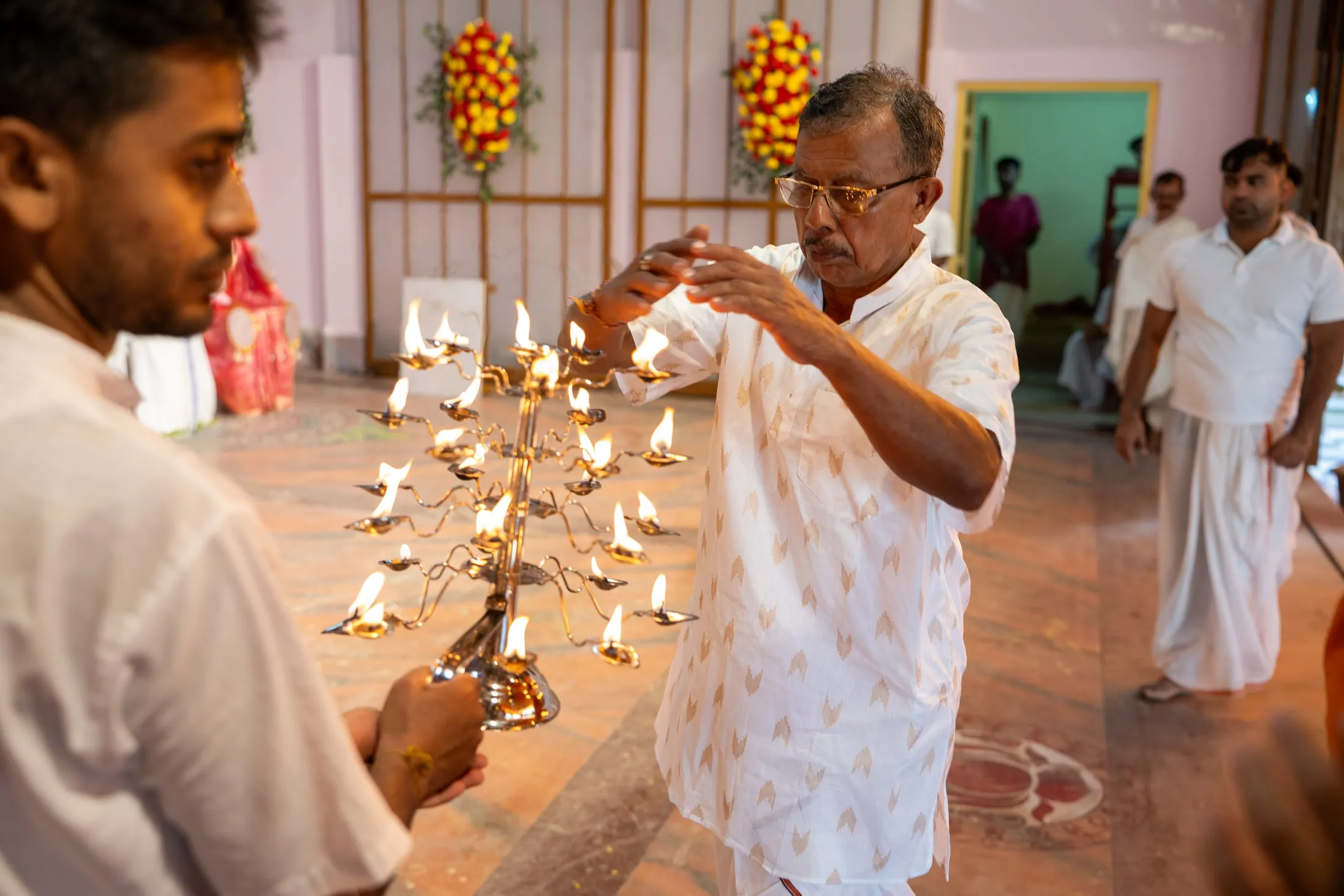 The tiered arati lamp stand being lit during Durga Puja