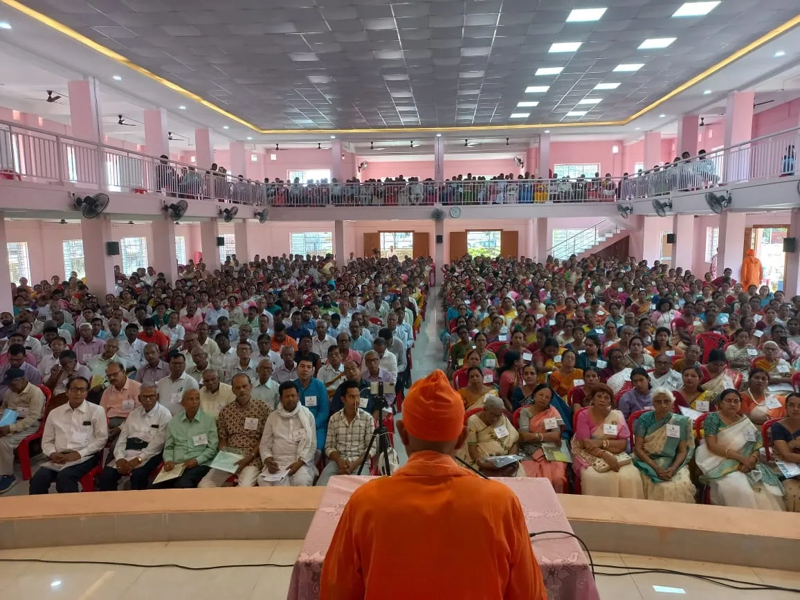 A monk addressing a full hall of delegates at Bhakta Sammelan